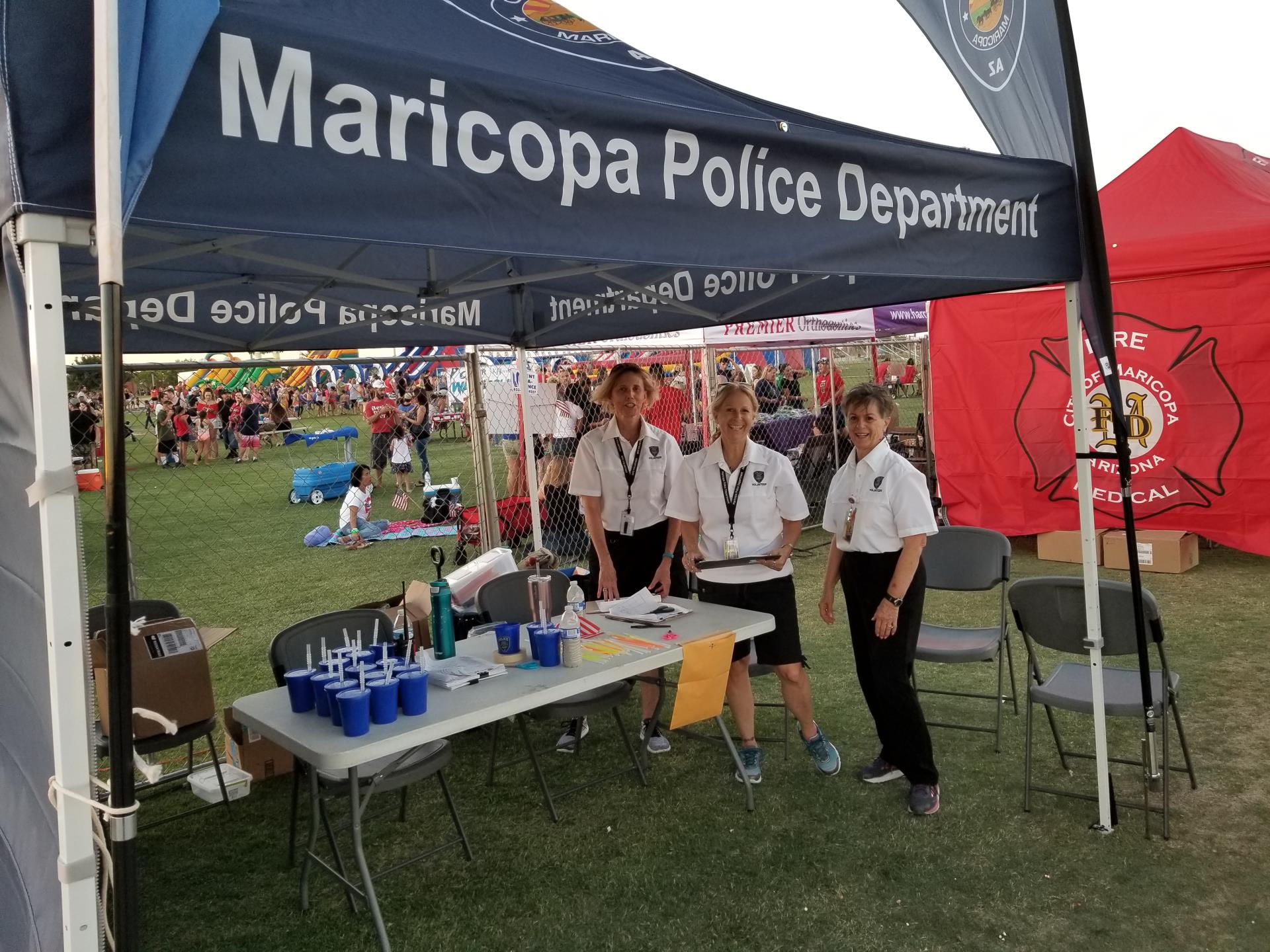 Photo of three volunteers standing under a MPD pop-up at a special event.